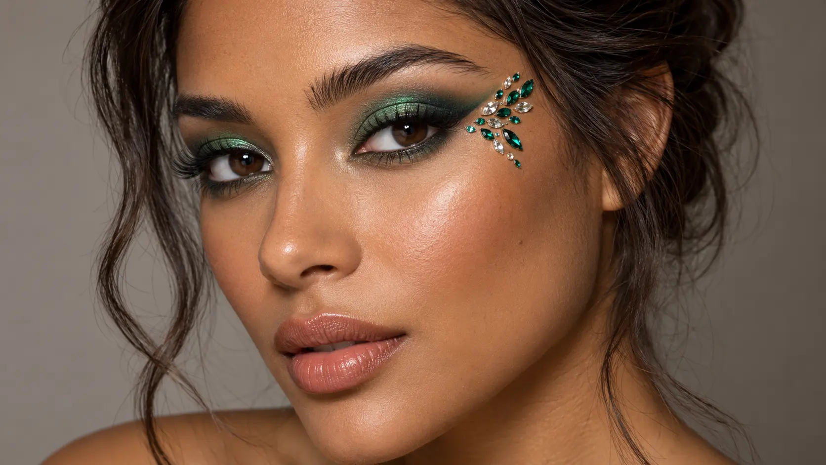 Emerald green smoky eye makeup with green and clear crystals arranged beside the outer eye.
